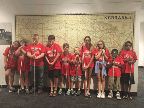 Students stand in front of a huge map of Nebraska, canes in hand