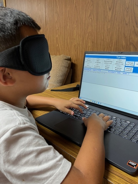 camper practicing keyboarding skills on laptop