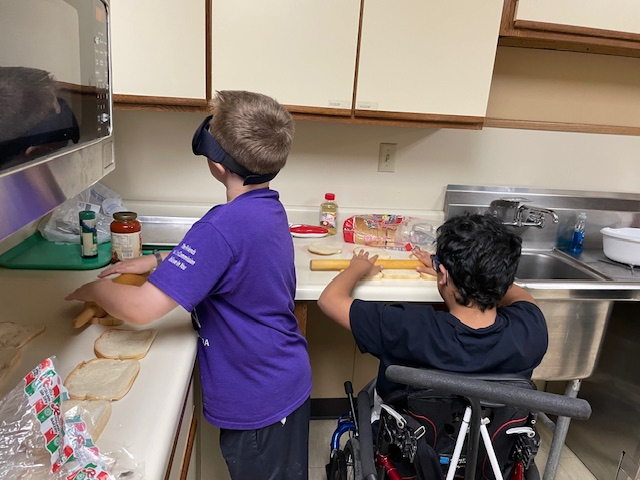 2 campers making pizza pockets in kitchen