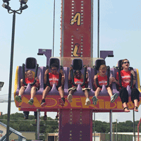 students beaming widely on free fall amusement ride