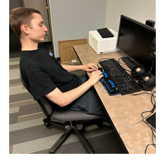 young man using braille display to access computer
